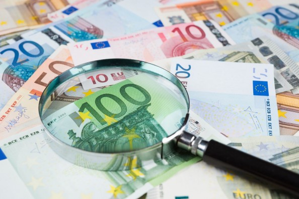 Finansų rinkos dalyvių priežiūra-padidinamasis stiklas ant banknotų.jpg